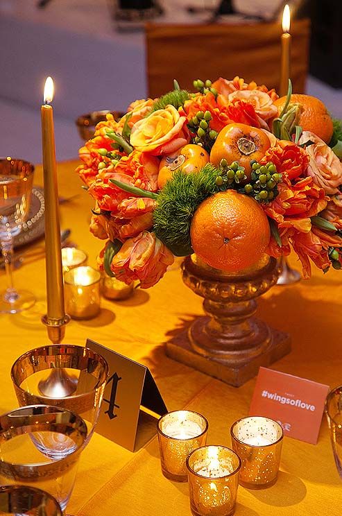 This low arrangement features parrot tulips, oranges, persimmons and roses in a ...